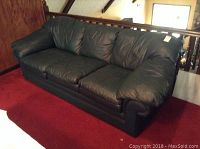 Front view of the green leather Benchcraft sofa showing seat cushions, armrests, and overall length.