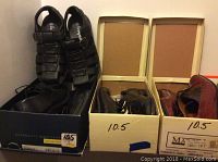 Three boxes showing men's shoes with sizes 10.5 and 9 marked on the boxes. Black leather dress shoes and sandals visible.