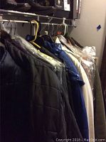 Men's coats hanging on a rack in various colors including blue, black, cream, and brown.