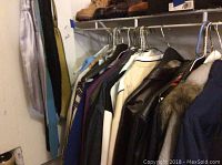 Hanging variety of men's coats and jackets in various colors and materials on a clothing rack.