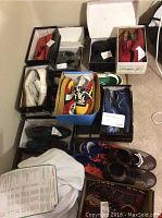 Seventeen pairs of men's shoes arranged on floor and mostly in boxes showing various styles and colors.