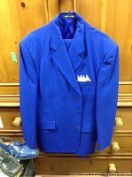 Blue men's suit jacket hanging on wooden background with blue dress shoes below
