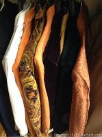 Photo of nine men's sport coats on hangers in various colors and patterns including white, orange, paisley, velvet, black, tan, and other colors.