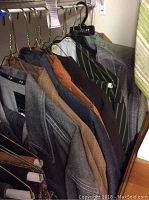 Photo showing 8 leisure suit jackets hanging on a rack in assorted colors and patterns including brown, grey, blue, and green striped.