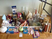 Wide view of the entire assortment on floor including candles, holders, wax boxes, and decorative candle items
