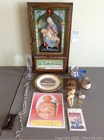 Full overview of all religious items displayed on a flat surface including 3D wall decor, rosary, prints, figurines, and medals