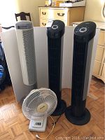 Photo showing two black Seville Classic tower fans, one white Seville Classic tower fan, and one white Sears table fan displayed against a white backdrop.