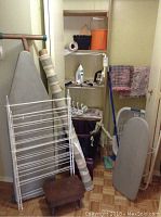 Photo of laundry room items showing two ironing boards, drying rack, laundry basket, step stool, and wooden floor