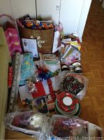 Wide shot showing assortment of gift bags, tissue paper, ribbons, plates, and wrapped items laid out on a table
