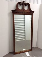 Full view of vintage wooden framed mirror with decorative carved top edge.