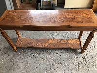 Full view of rectangular wooden sofa or hall table showing the wood grain pattern on top and bottom shelf, carved legs and overall structure.