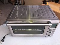 Front view of Breville convection toaster oven with glass door closed, showing handle, control knobs and digital display.