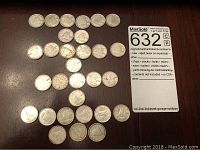 Top view of 28 Canadian dimes arranged on a dark wooden surface, showing the reverse side with the traditional Bluenose schooner design on most coins.