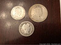 Photo of three coins on a dark wooden surface showing the obverse side of the 1902 Canadian dime, 1903 Canadian quarter, and 1902 American dime with visible wear and details.