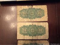 Front side of two Dominion of Canada 25 cent bank notes showing age-related creasing and wear with green denomination marking.