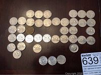 Top view of 48 Canadian nickel coins laid out on a dark surface, showing the reverse side with beaver or other typical designs.