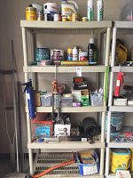 Full view of the five shelf plastic shelving unit filled with cans, boxes, caulk guns, and other hardware and finishing supplies.