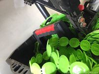 Close-up of a nail gun with green coiled fasteners with plastic caps loaded.