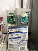 Plastic containers filled with Backer-On 1 1/4 inch screws and a box of Rapid Set concrete mix showing usage information on the label.