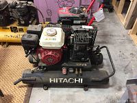 Front view showing entire compressor assembly on horizontal tank with 'Hitachi' logo
