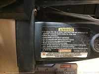 Close-up photo of the warning label on the Ryobi mini miter saw showing safety instructions and laser radiation warning.