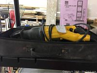 DeWalt reciprocating saw in black soft carrying case on a workbench, showing the full length of the saw and case.