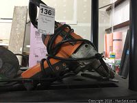 Side view of an orange and black Ridgid drill with power cord wrapped around the tool, showing the chuck and handle.