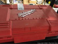 Closed red plastic carrying case with Milwaukee Heavy Duty logo on lid.
