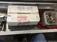 Box of Max USA collated roofing nails with some loose nails visible plus part of red roof jacks.