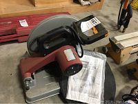 Photo showing the cut off saw, featuring the handle, motor housing, and base plate.