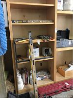 Shelf showing a variety of drywall finishing tools, construction levels and some drywall finishing compound containers.