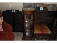 Lot includes a vintage curio cabinet, upholstered chair, and black extendable fireplace screen.