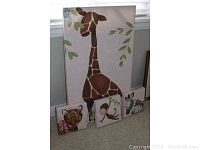 Four children's animal-themed wall art paintings arranged in front of a window, showing the giraffe, zebra, tiger, and monkey.