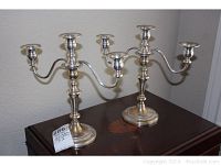 Pair of three-arm sterling silver weighted candelabras seen from front with some tarnish.