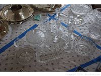 Photo showing multiple crystal items including cut crystal candlesticks, bowls, vases, and dishes on patterned cloth