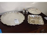 Overview of all five pieces on wood surface: large scalloped tray at front left, square scalloped dish front right, round stepped tray back right, salt and pepper shakers center, small round dish