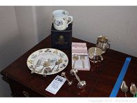 Royal Worcester children's plate with sterling silver utensils and teething items arranged on a wooden table, with children's cup in original box.
