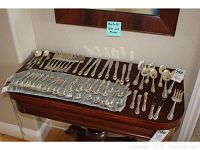 Overview of 60 pieces of flatware and serving pieces arranged on table
