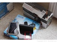 Photo showing box for Brookstone Neck and Shoulder Massager, Tanita scale box, Nook e-reader device, Tumi power pack box with case visible, and power stick.