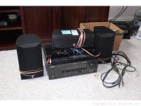Yamaha AV receiver with three Yamaha speakers and cables on carpeted floor.