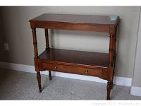 Front view of hall table showing turned legs, lower shelf with drawer, and top surface.