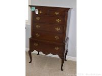 Full view of the six-drawer dresser standing on cabriole legs with decorative carved details and brass drawer pulls.