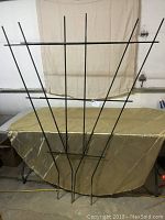 Full view of the large fan-shaped metal garden trellis, showing its V design and horizontal supports.