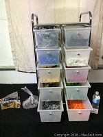 Front view of rolling storage cart with 10 semi-transparent drawers filled with assorted LEGO pieces sorted by color.