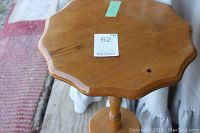 Close-up of small wooden three-legged table with scalloped edges top showing wood grain and finish