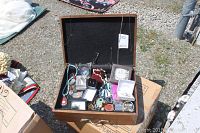 Wooden canteen box open with assorted costume jewelry pieces inside and on top, showing the variety and storage size.