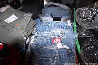 Photo showing stacks of boys pants including Levi's denim jeans and green casual pants on table