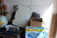 Photo showing two world globes, stacked binders, file hangers, and a box of large size bubble mailers.