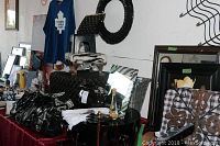 Black sequin wreath hung on wall, five ladies purses including black quilted and patent finishes arranged on table, zebra print footstool, rectangular zebra framed mirror leaning against wall