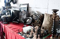 Table with black and beige decorative pillows, chess and checker board with chess pieces, clocks, glass dish, framed art, and mirror.